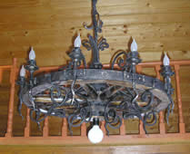 Forged chandelier stylized as a cart wheel.